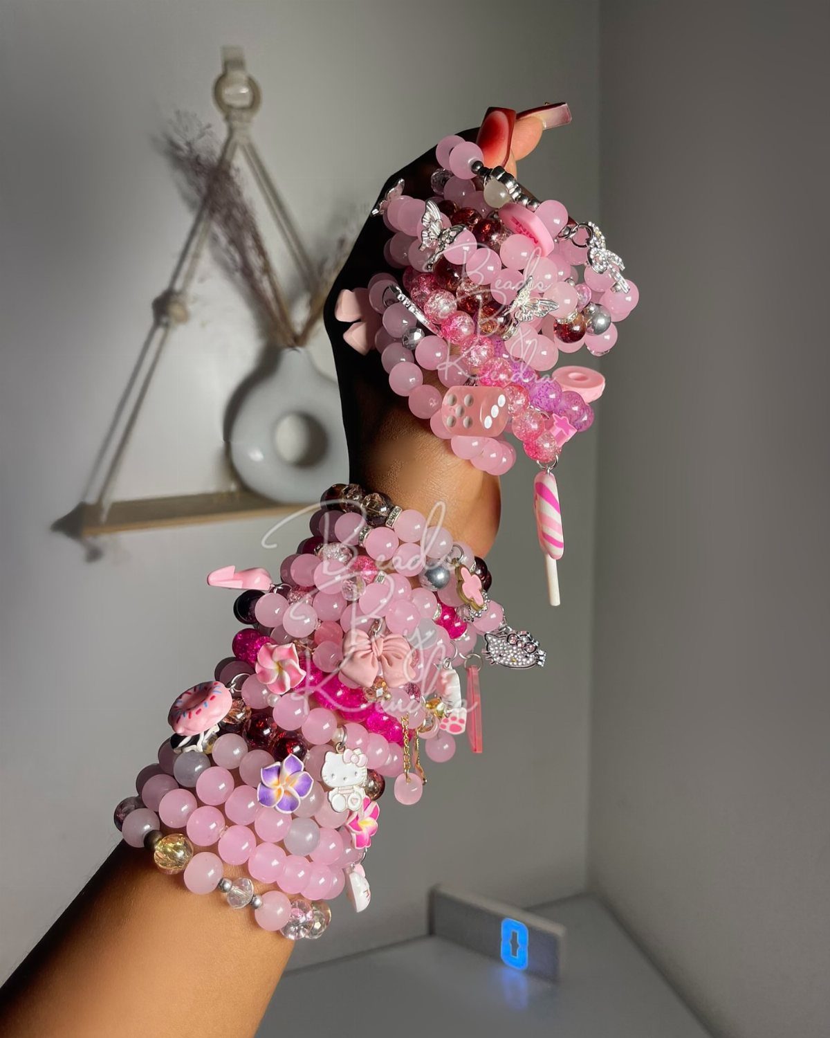 11 Beaded Jewelry DIY Bracelets Ideas for Every Style 3 Stacked pink beaded bracelets with various charms worn on a person's arm.