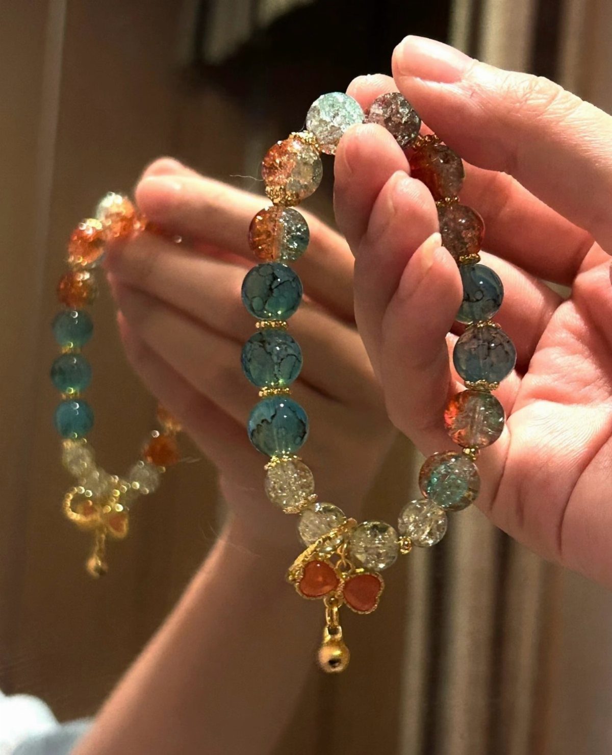 11 Beaded Jewelry DIY Bracelets Ideas for Every Style 9 Crackle glass bead bracelets in blue and orange held by two hands.