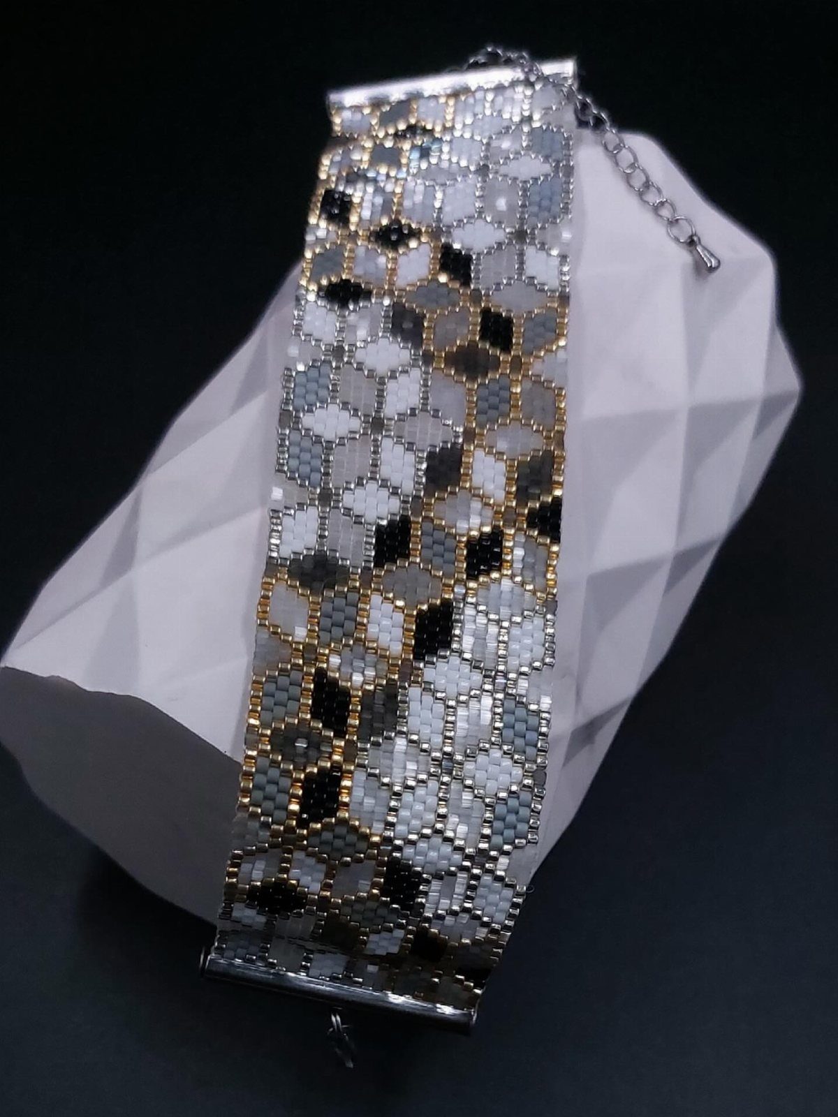 11 Beaded Jewelry DIY Bracelets Ideas for Every Style 6 Wide beaded cuff bracelet with grey and black geometric patterns on white stand