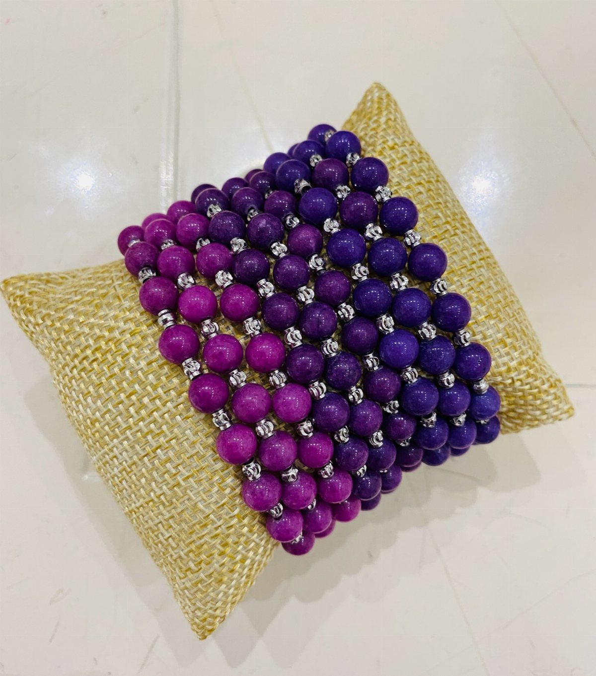 11 Beaded Jewelry DIY Bracelets Ideas for Every Style 4 Purple and magenta ombre beaded bracelets resting on a tan burlap cushion.