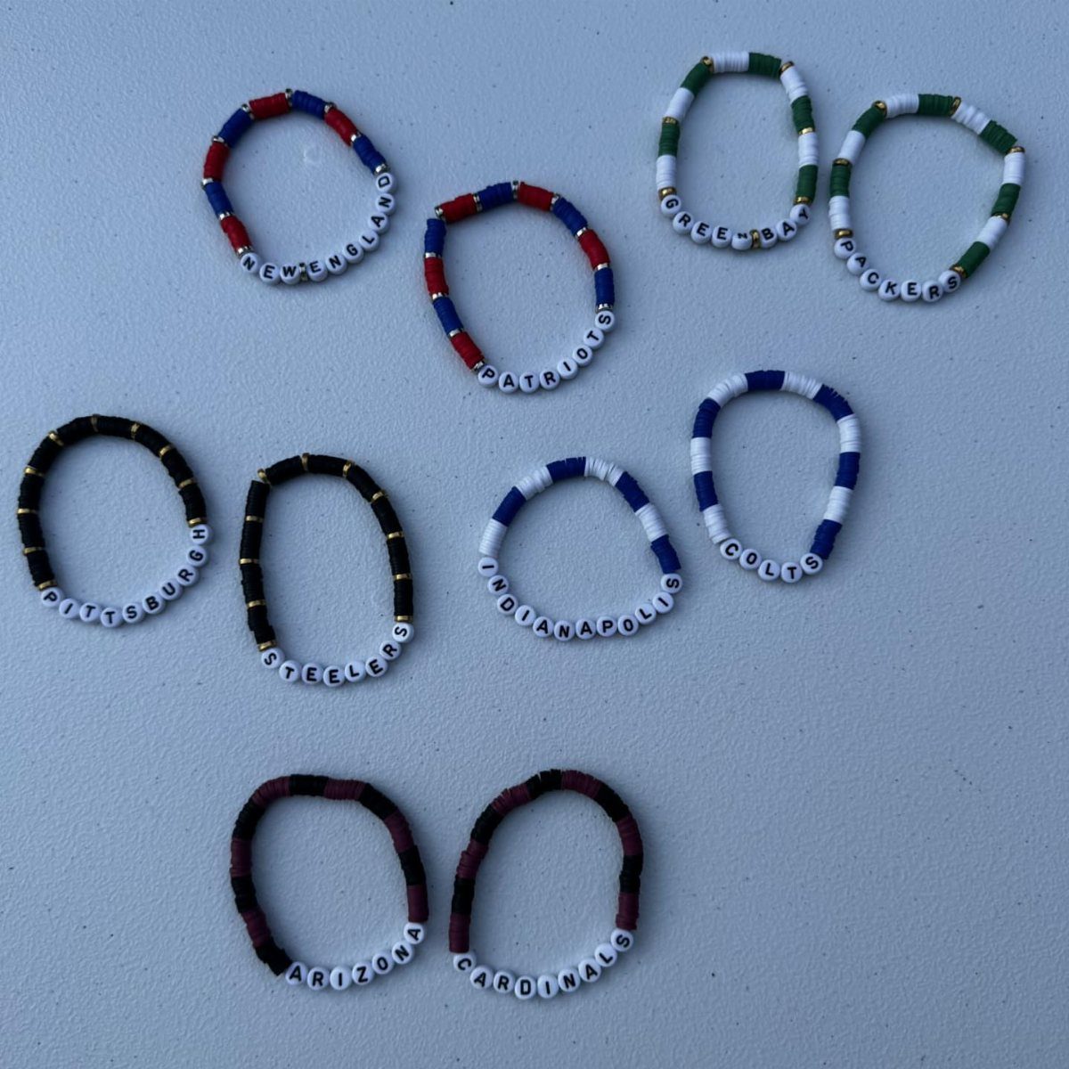 11 Beaded Jewelry DIY Bracelets Ideas for Every Style 11 Beaded bracelets with team colors and letter beads spelling NFL team names.