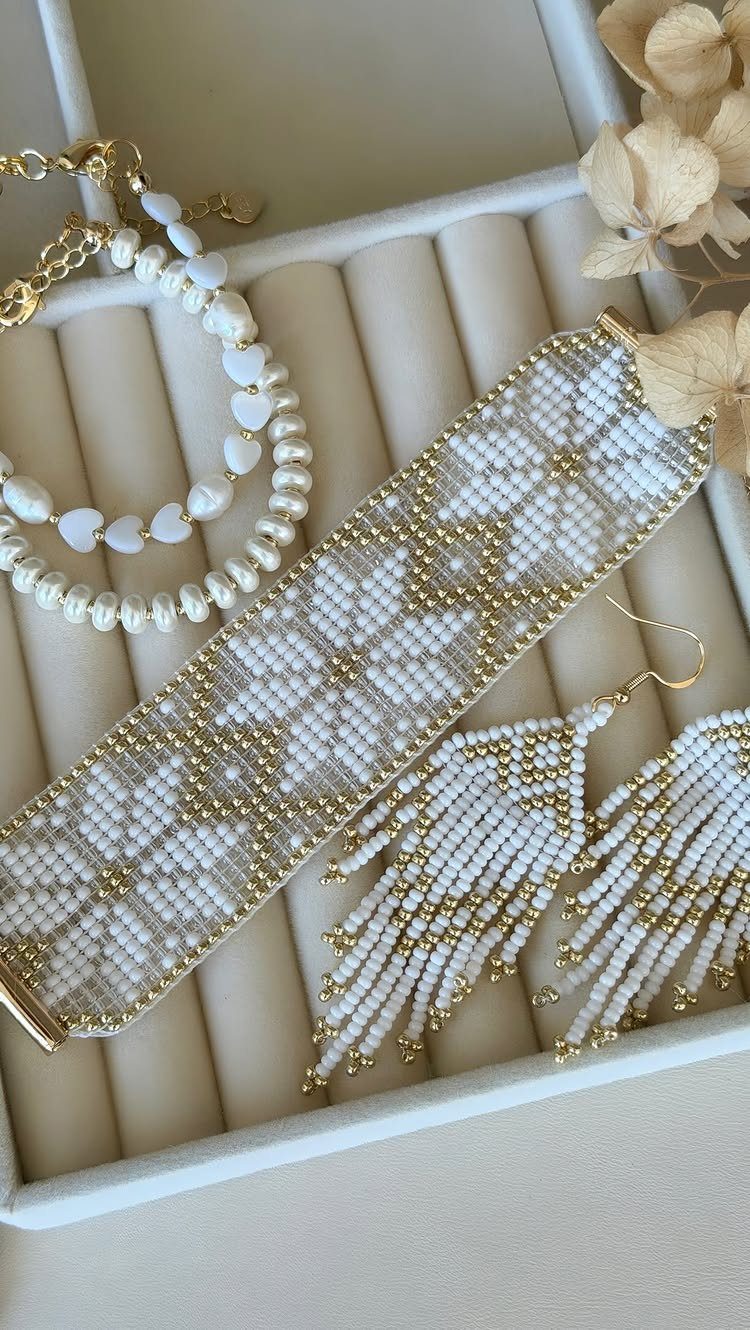 White and gold beaded cuff bracelet, earrings, and necklaces in a jewelry box.