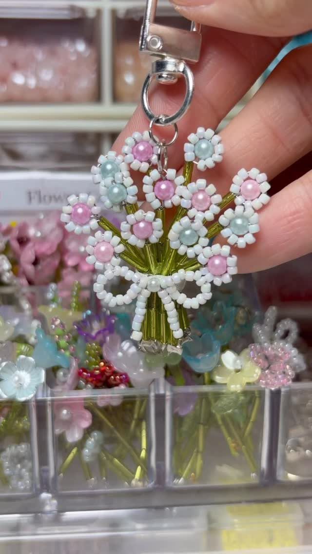16 Beaded Jewelry Ideas to DIY (Bracelets, Necklaces & Earrings) 5 Beaded flower bouquet keychain with white, pink, and blue beads and green stems.