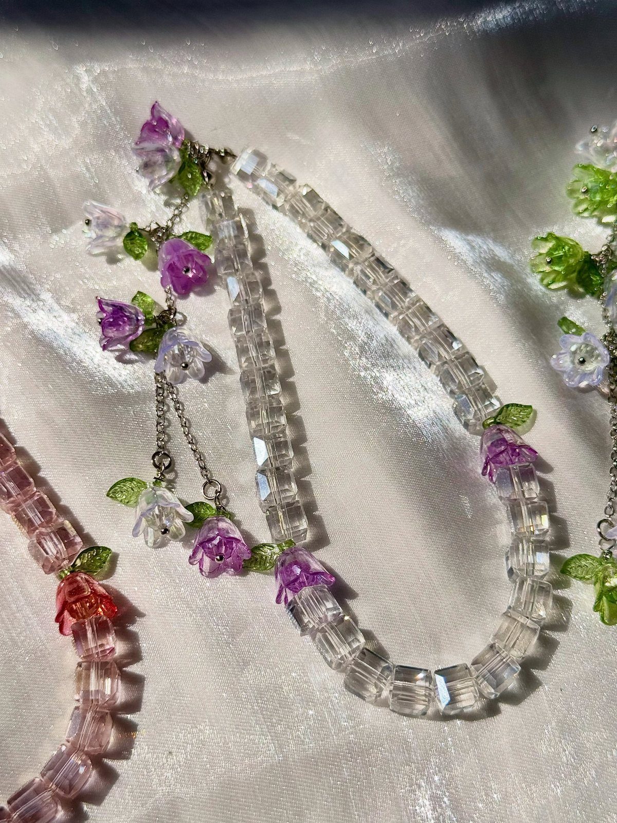 16 Beaded Jewelry Ideas to DIY (Bracelets, Necklaces & Earrings) 2 Beaded necklaces with clear and pink crystals and small purple flower accents.