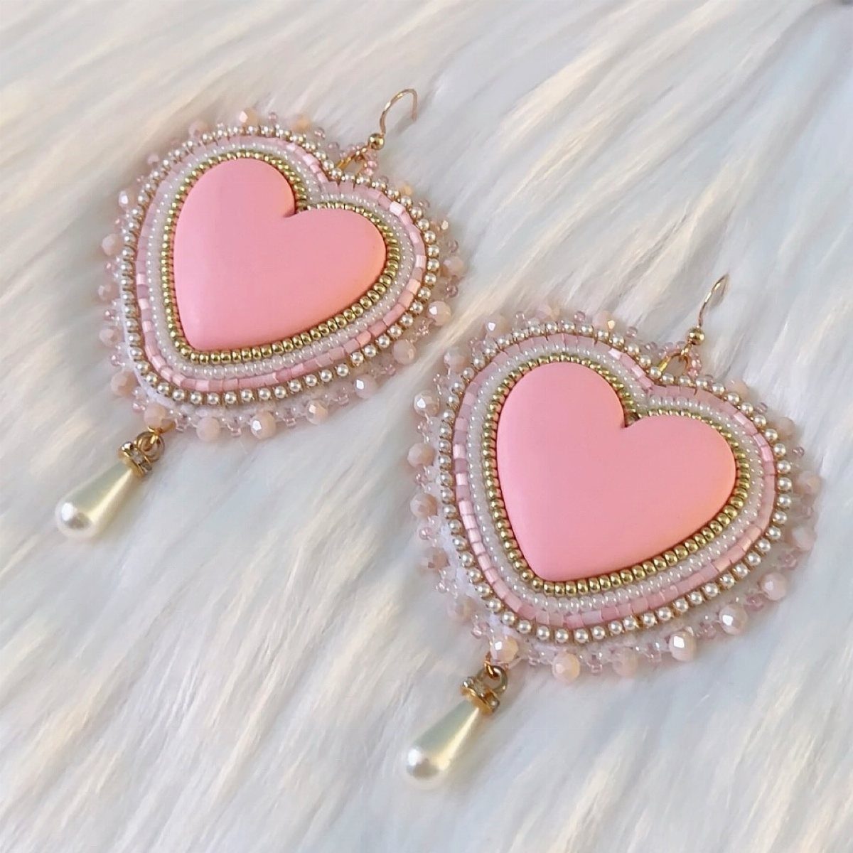 16 Beaded Jewelry Ideas to DIY (Bracelets, Necklaces & Earrings) 4 Heart-shaped beaded earrings with pink centers and pearl drops on white fur.