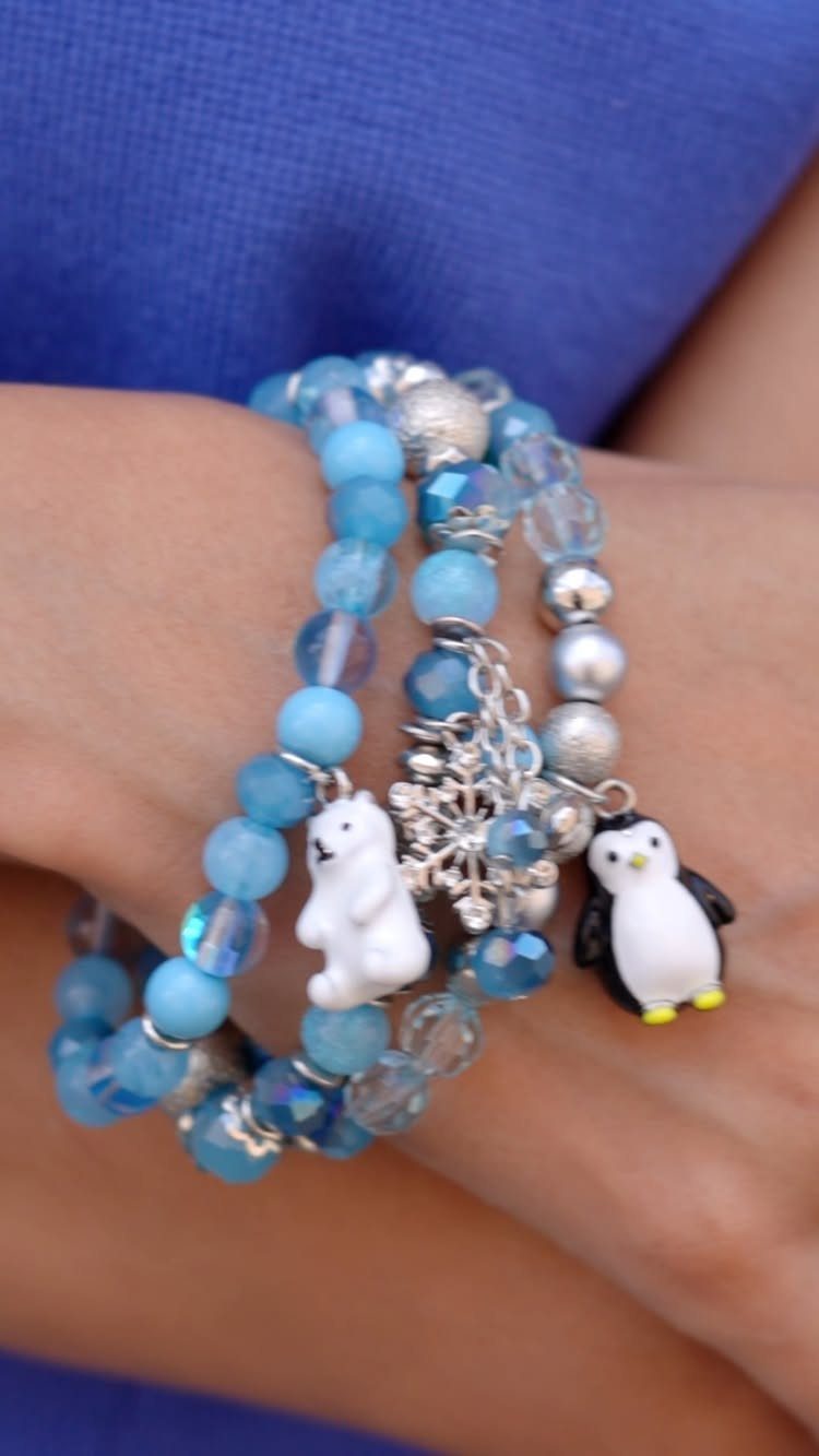16 Beaded Jewelry Ideas to DIY (Bracelets, Necklaces & Earrings) 16 Blue beaded bracelets with polar bear and penguin charms on a person's wrist