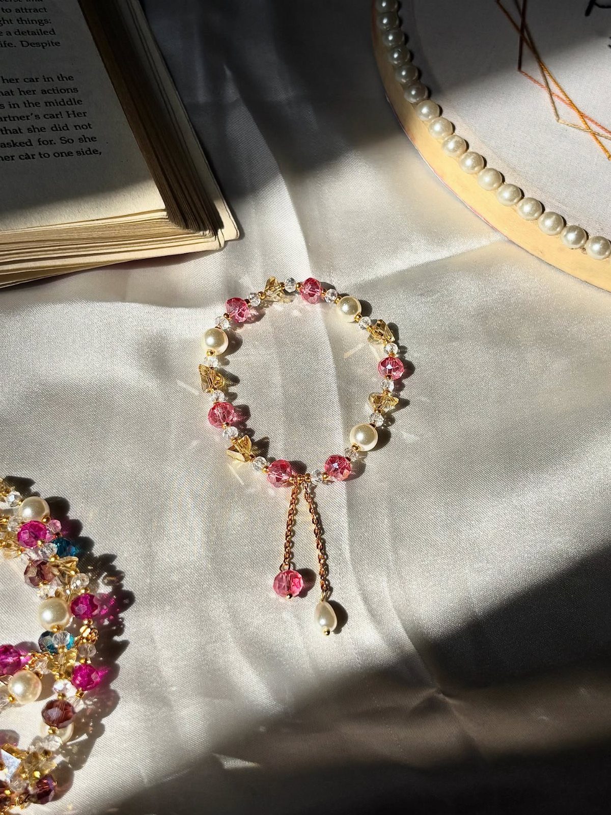 16 Beaded Jewelry Ideas to DIY (Bracelets, Necklaces & Earrings) 12 Handmade beaded bracelet with pink crystals and pearls on white fabric