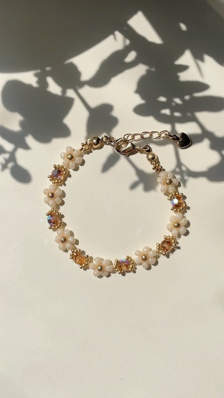 16 Beaded Jewelry Ideas to DIY (Bracelets, Necklaces & Earrings) 1 Beaded bracelet with white flowers and iridescent beads on a white surface