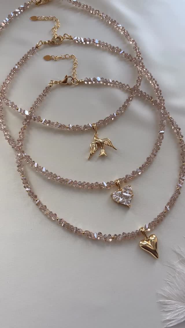 16 Beaded Jewelry Ideas to DIY (Bracelets, Necklaces & Earrings) 15 Three beaded necklaces with gold bird and heart charms on a white background