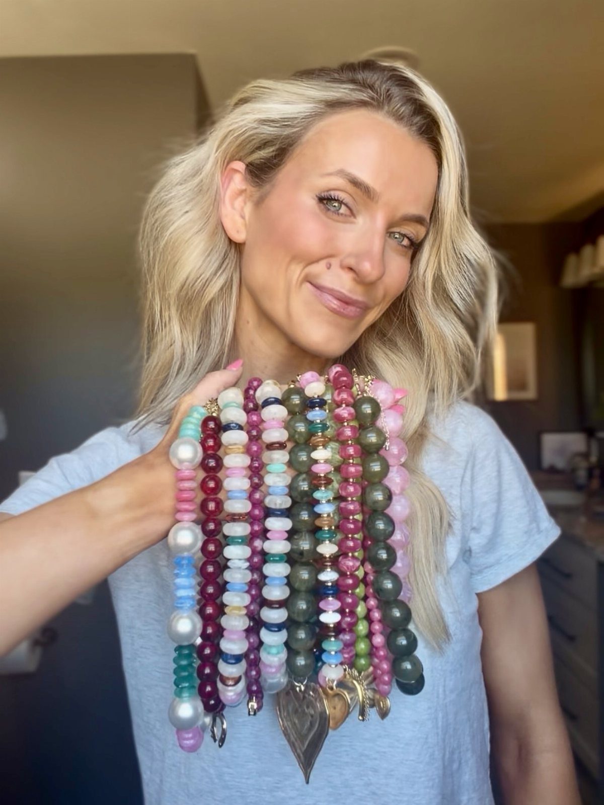 16 Beaded Jewelry Ideas to DIY (Bracelets, Necklaces & Earrings) 8 Woman wearing layered colorful beaded necklaces with a large metallic heart pendant charm.