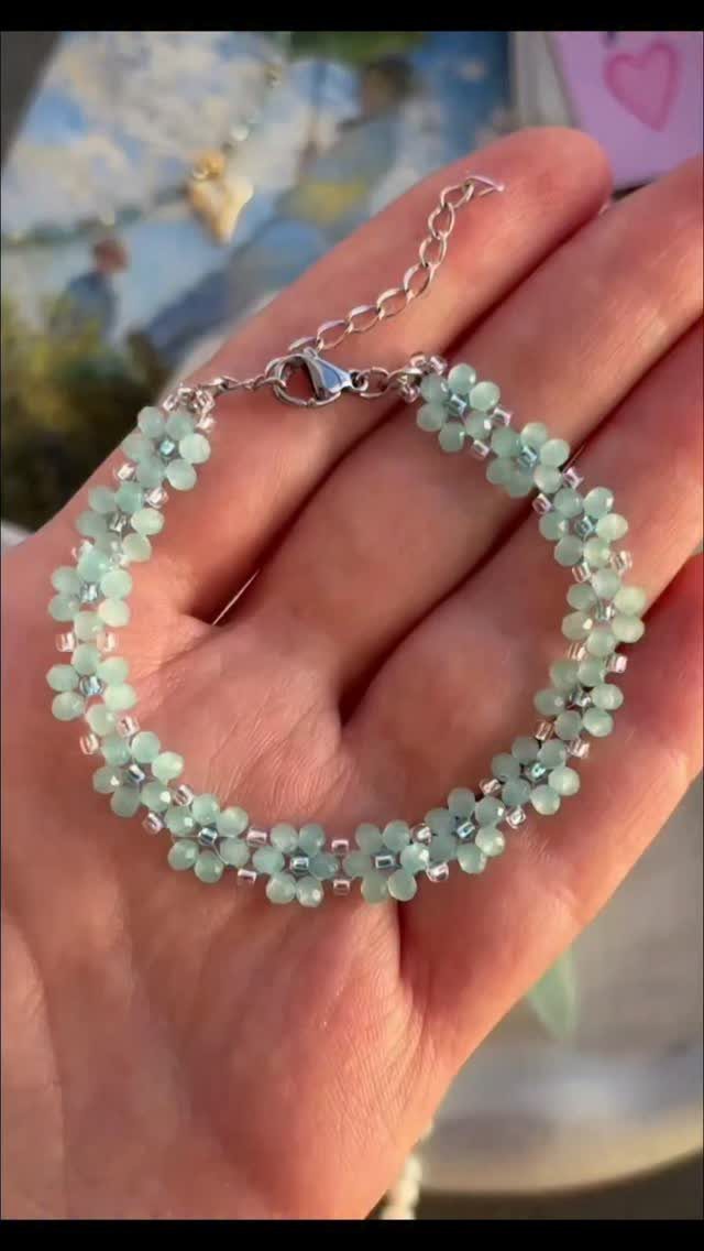Light green beaded floral bracelet held in a person's open palm
