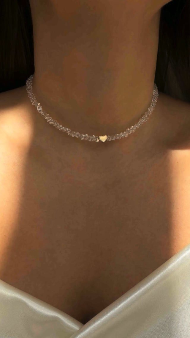 Clear faceted bead choker necklace with a gold heart charm on a person