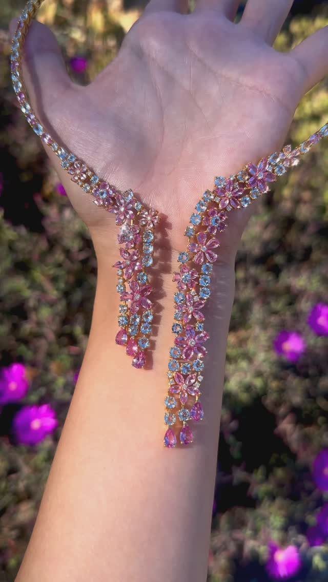 Beaded Jewelry Trends 2026: 8 Styles From Chunky Necklaces to Charm Accents 7 Beaded necklace with pink and blue crystal flowers held against purple flowers.