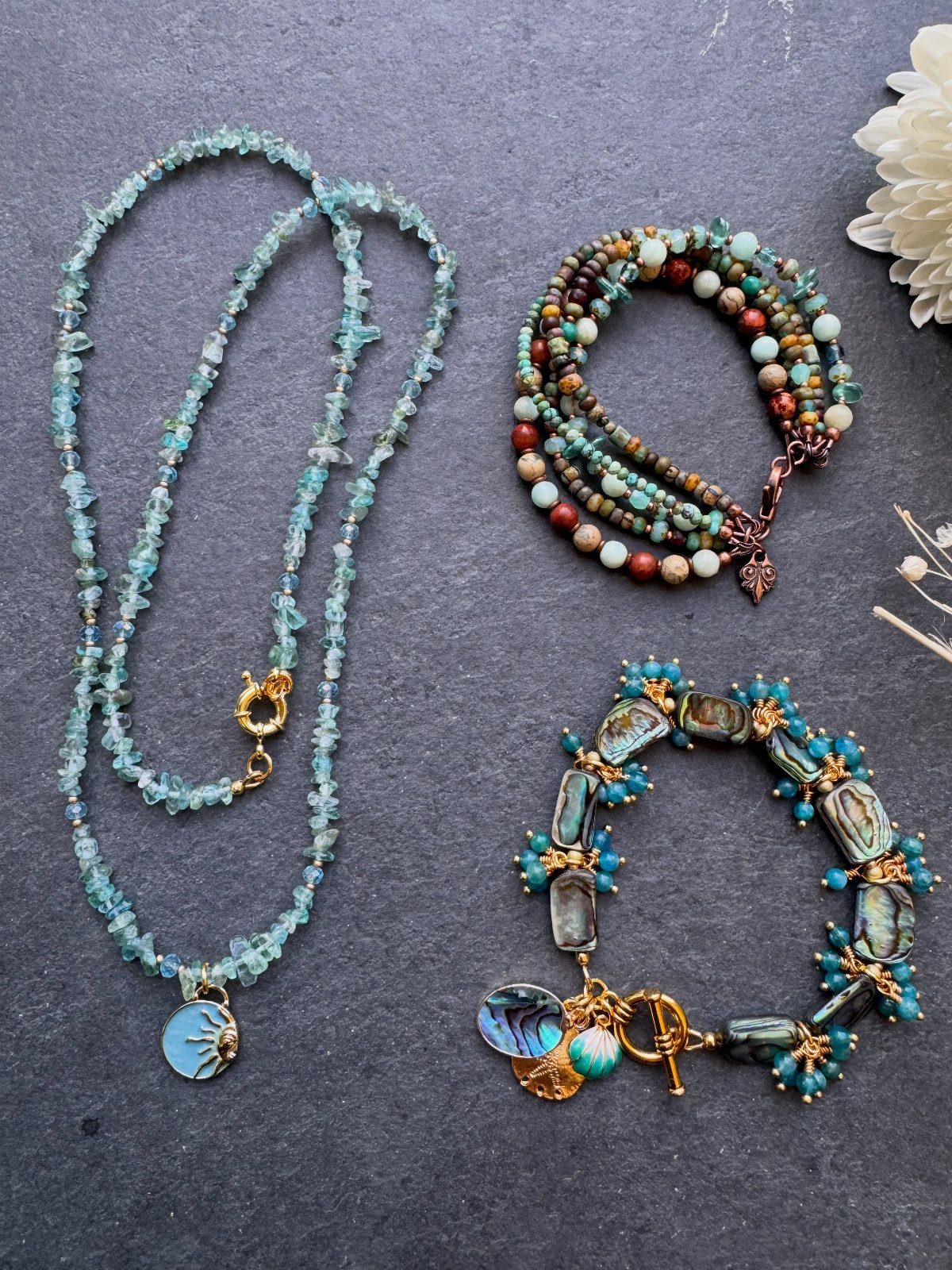 Beaded Jewelry Trends 2026: 8 Styles From Chunky Necklaces to Charm Accents 2 Beaded jewelry including a light-blue gemstone necklace and two turquoise and brown bracelets.