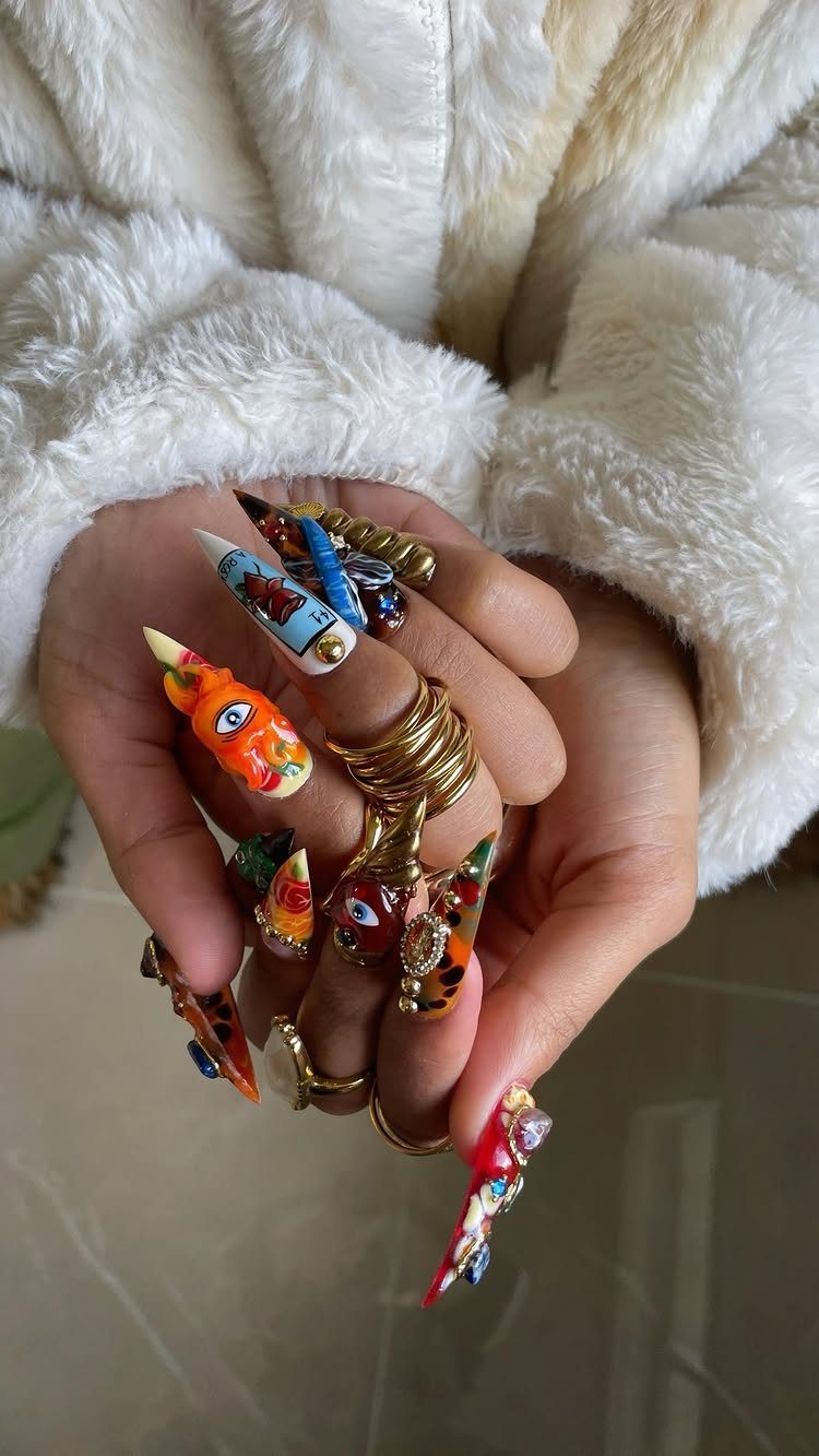 Bold Gold Jewelry: 9 Ways to Wear the Trend in 2026 9 Hands with chunky gold rings and colorful, long 3D decorative nail art.