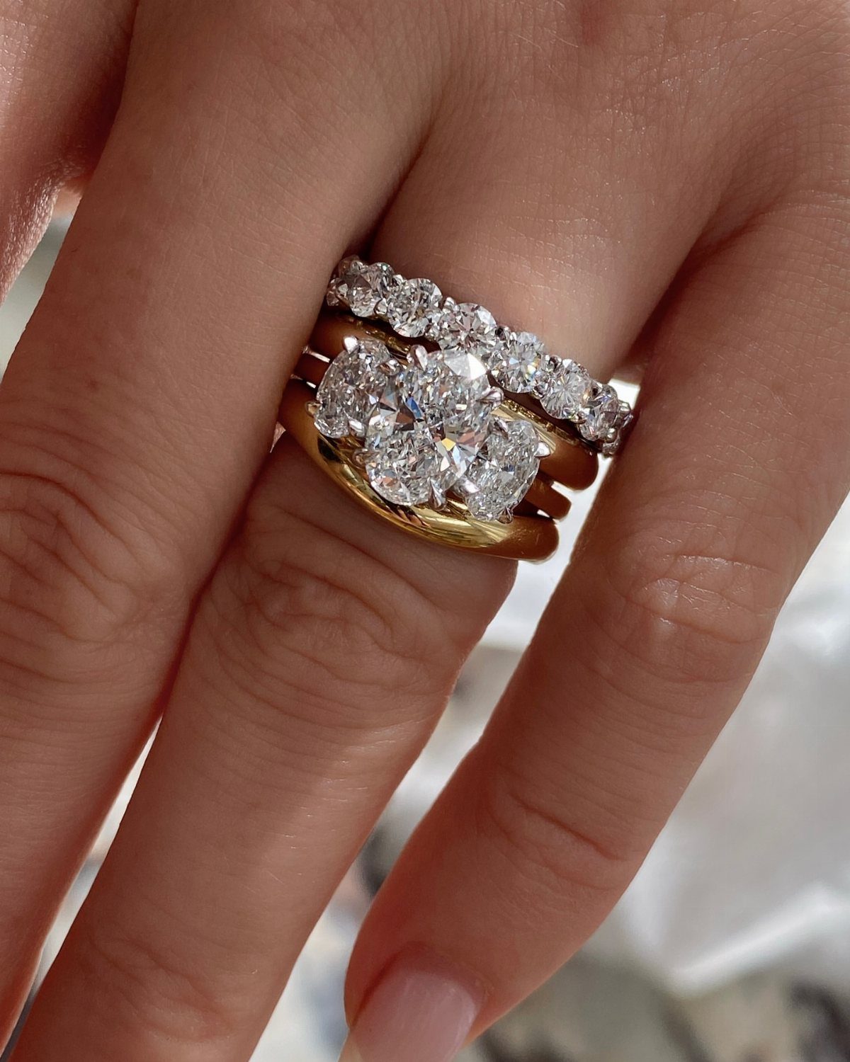 Bold Gold Jewelry: 9 Ways to Wear the Trend in 2026 1 Stacked gold and diamond rings on a finger, featuring mixed gold metal tones.