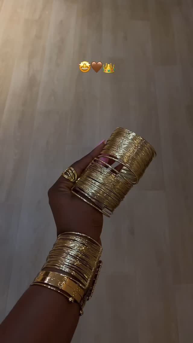 Bold Gold Jewelry: 9 Ways to Wear the Trend in 2026 5 Gold bangles stacked on wrists and a gold ring on a hand.