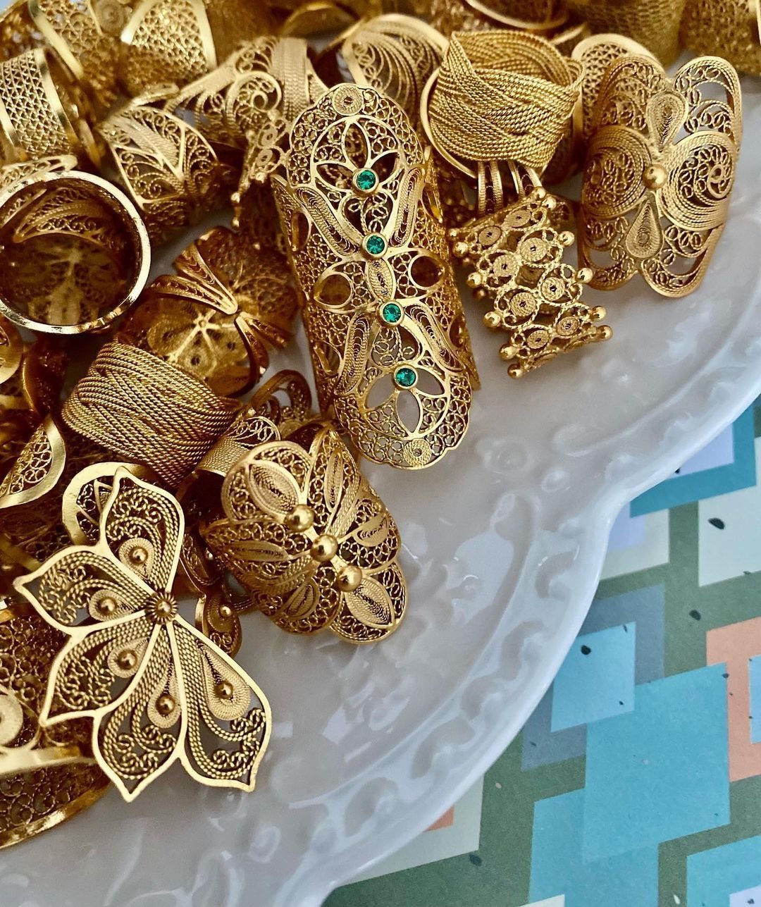 6 Cali Gold Rings for Hearts, Chunky Bands and Twisted Styles 4 Gold filigree rings with intricate openwork designs on a white scalloped tray.