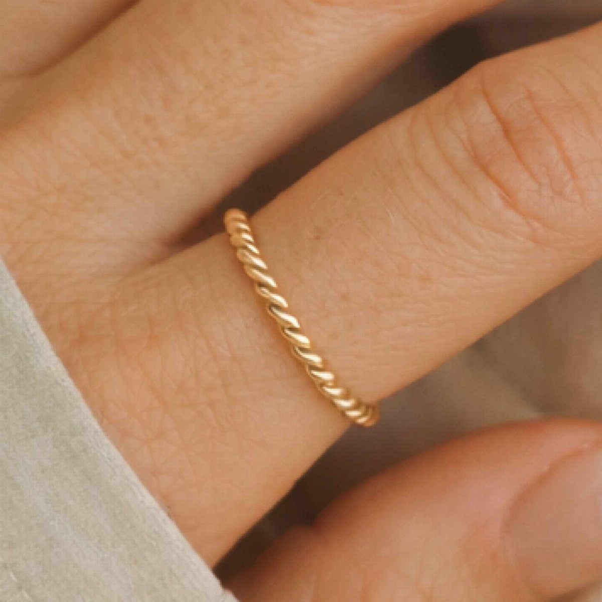 6 Cali Gold Rings for Hearts, Chunky Bands and Twisted Styles 5 Thin gold twisted rope ring worn on a person's finger
