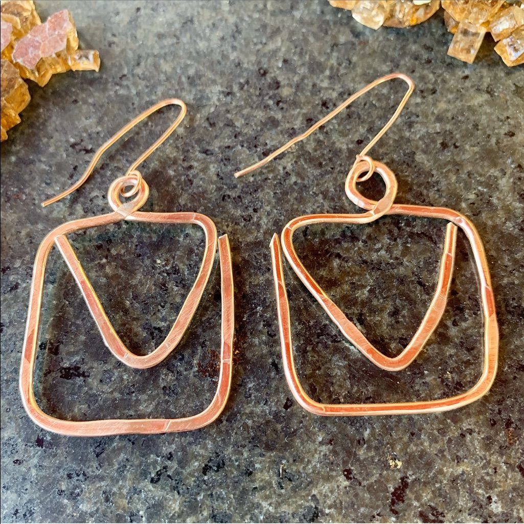 Copper wire earrings with geometric square and triangle shapes on grey stone.