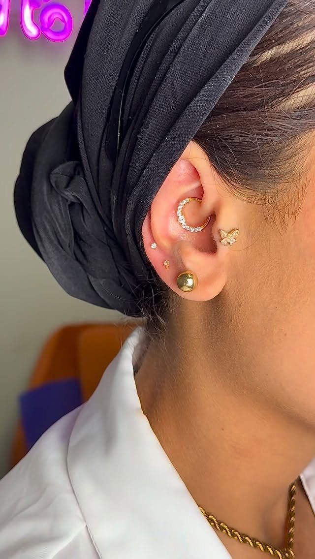 Ear with multiple gold piercings including a hoop and butterfly stud