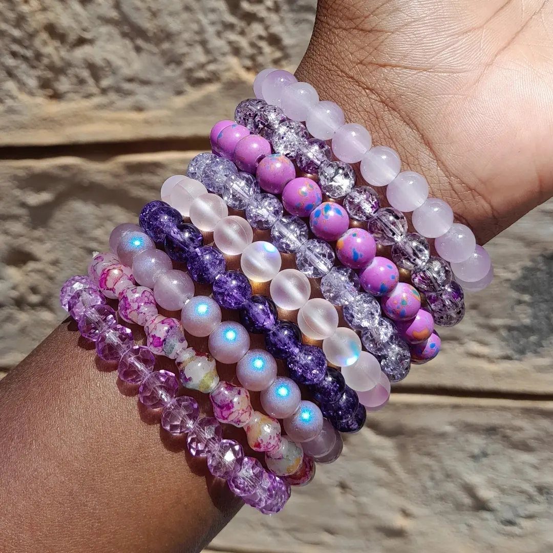5 DIY Bracelets: Easy Beads Projects With Stretchy, Multi-Strand & More 1 Stack of purple and white beaded bracelets worn on a person's wrist.