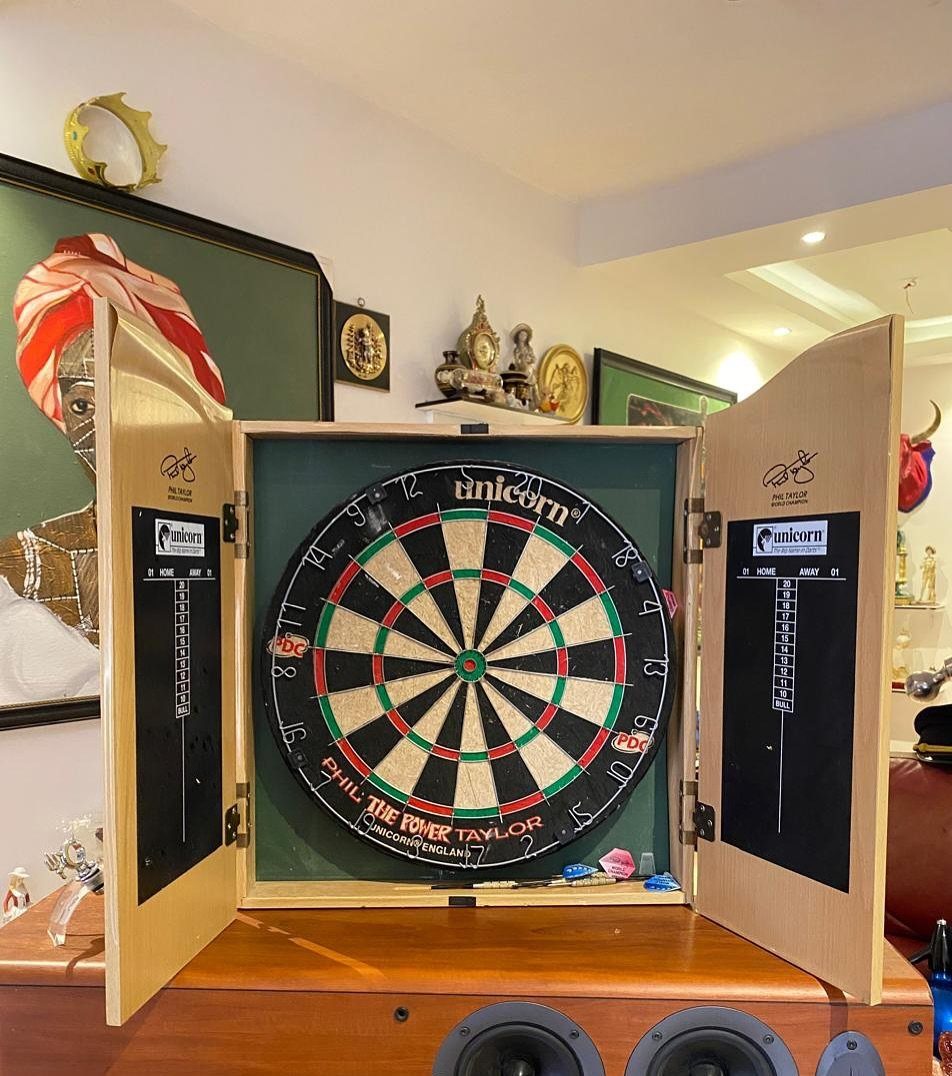 DIY Dart Board Backboard: 7 Clever Projects for Any Style 2 Dartboard mounted inside a wooden cabinet with open doors and a green background.