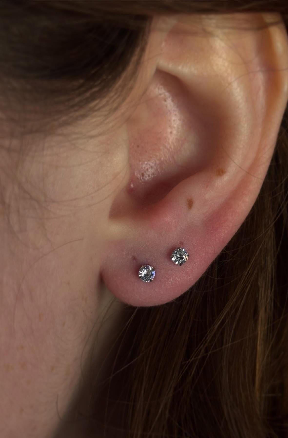 11 Ear Piercing Stack Inspo Ideas to Upgrade Your Look 11 Ear lobe with two small sparkling diamond stud earrings in a row.