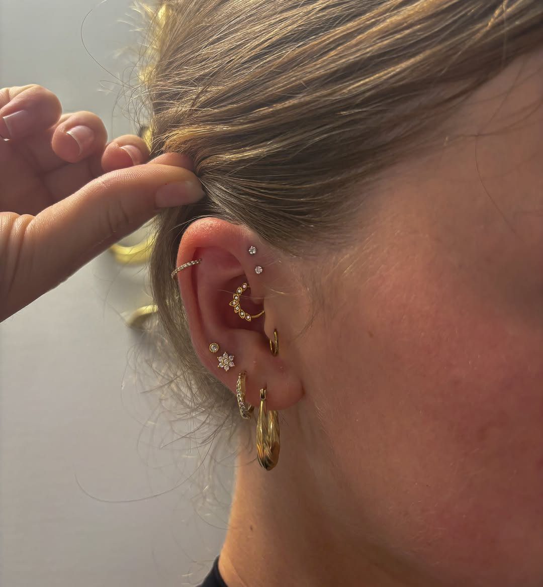 11 Ear Piercing Stack Inspo Ideas to Upgrade Your Look 6 Ear with multiple gold and diamond piercings arranged in a size gradation stack.