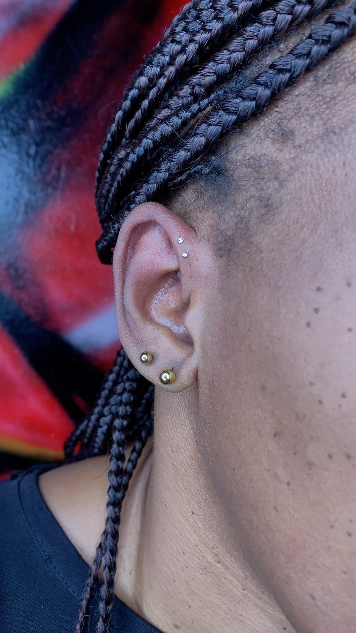 11 Ear Piercing Stack Inspo Ideas to Upgrade Your Look 7 Ear with a silver forward helix stud and gold lobe earrings, braided hair.