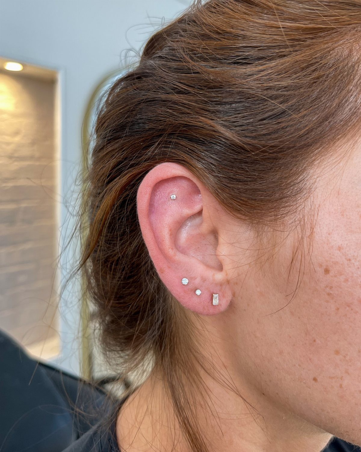 11 Ear Piercing Stack Inspo Ideas to Upgrade Your Look 10 Ear with silver stud earrings in the lobe and upper cartilage piercing.