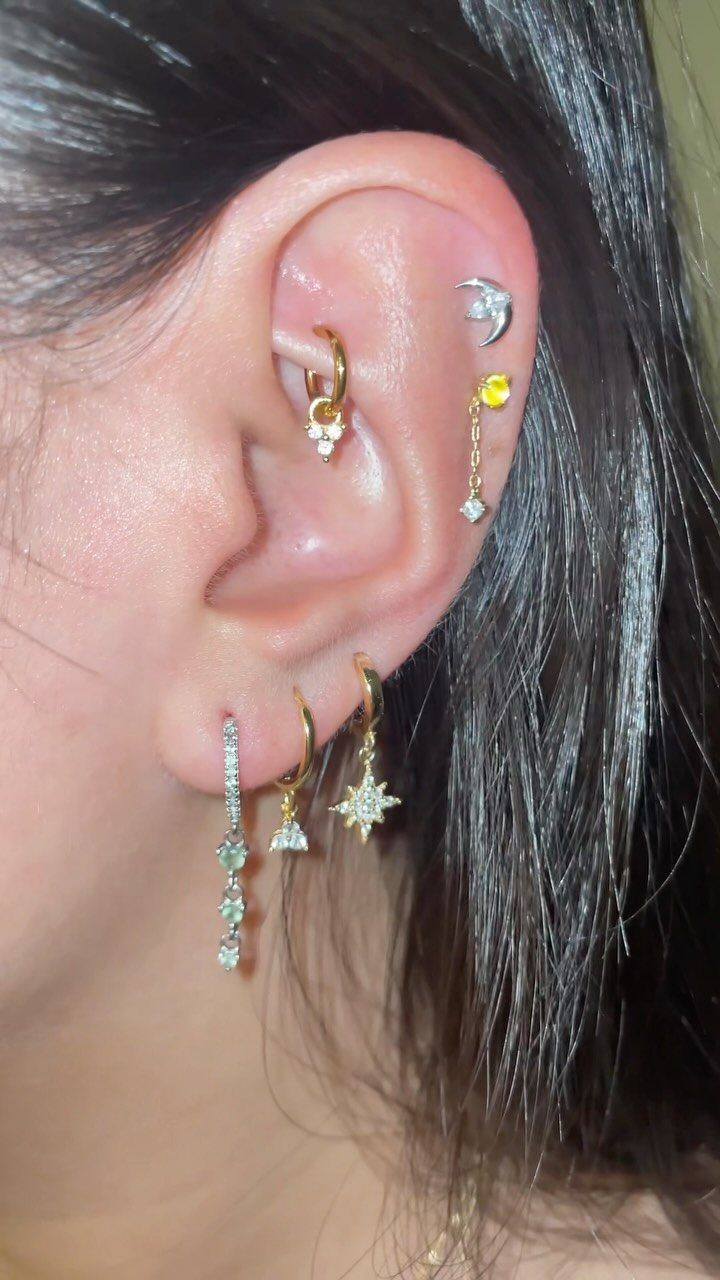 11 Ear Piercing Stack Inspo Ideas to Upgrade Your Look 5 Ear with multiple gold and silver piercings featuring stars and crystal studs.