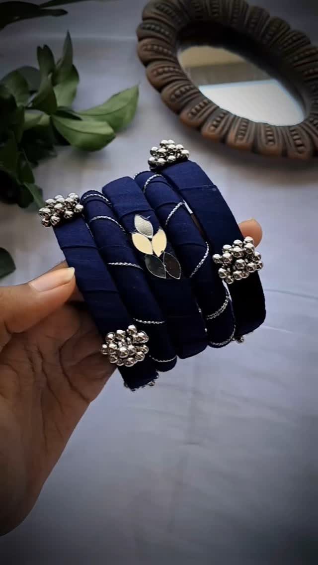 5 Fabric Jewellery Design Ideas for Necklaces, Bracelets and More 2 Navy blue fabric-wrapped bangles with silver beaded accents held in a hand.