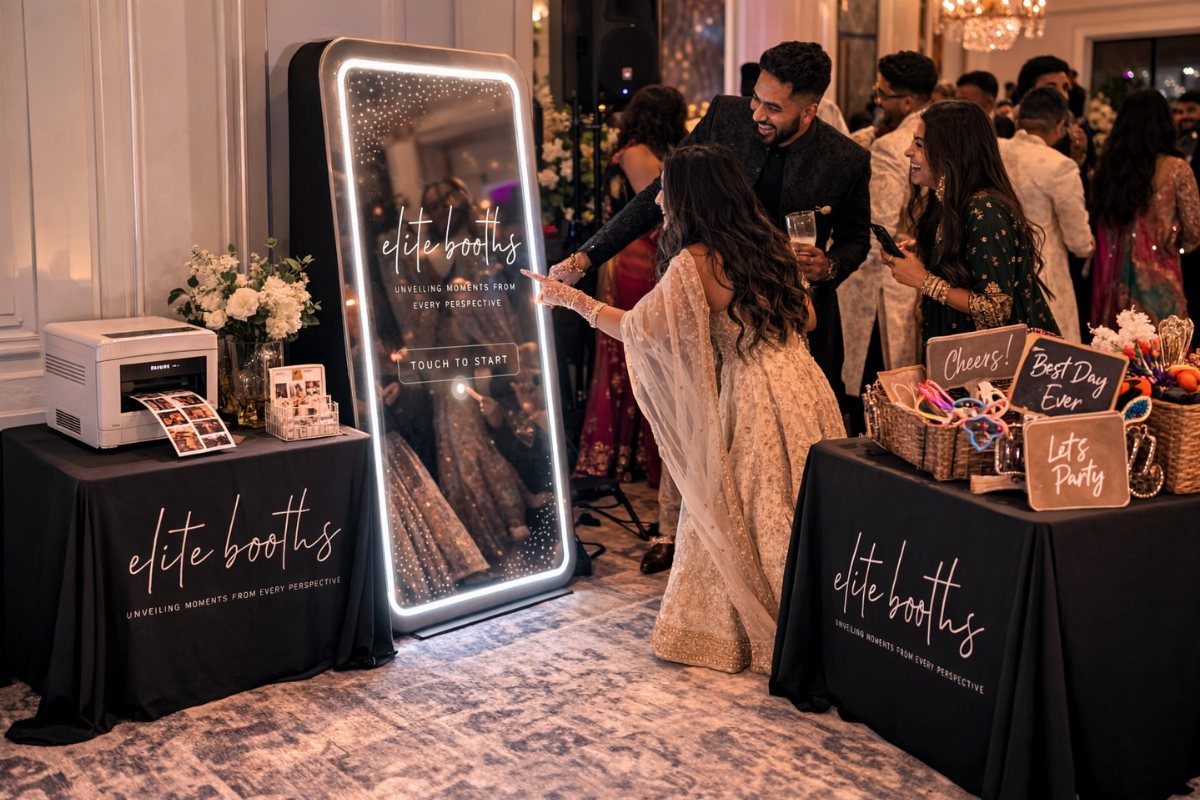 Mirror photo booth with guests in formal attire and prop tables at a wedding.