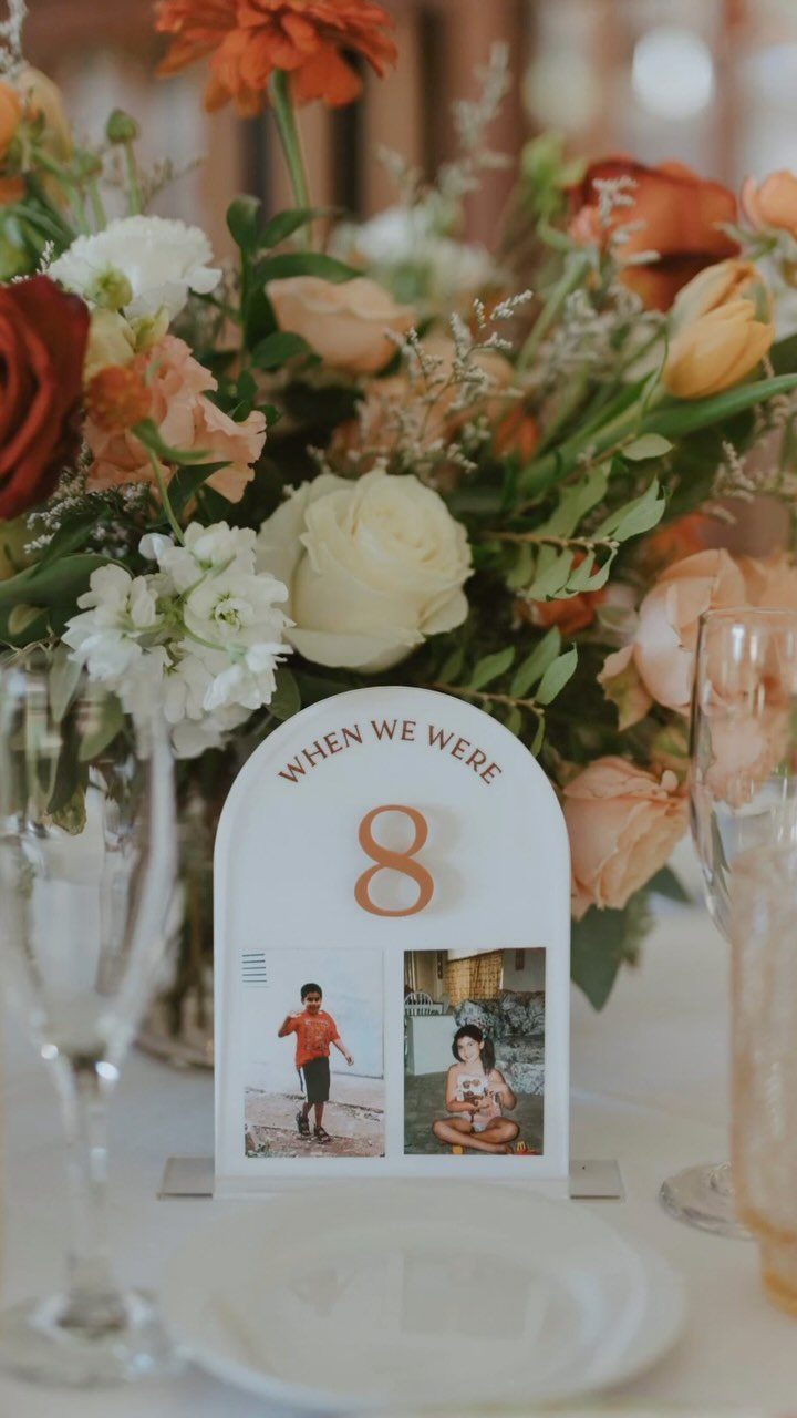 Arched table number card with childhood photos and floral arrangement on wedding table