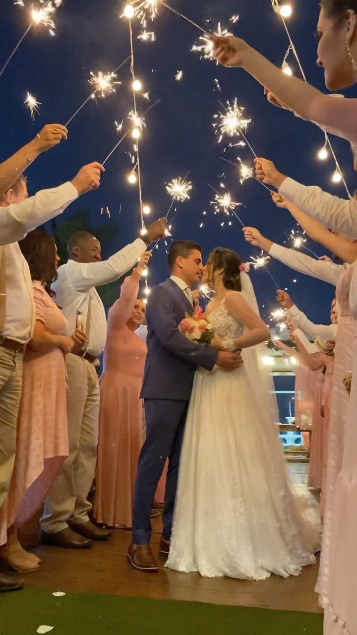 Bride and groom kissing under an arch of sparklers held by wedding guests.