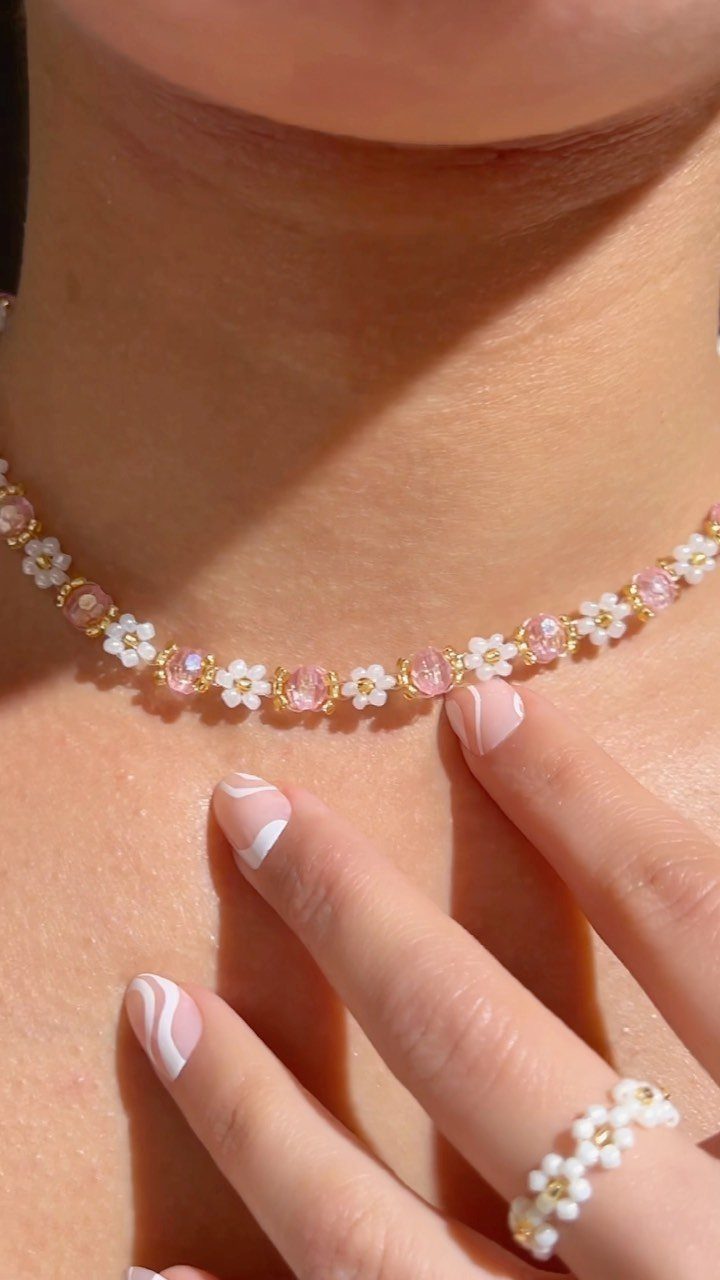 Handmade beaded necklace and ring with white flowers worn by a person