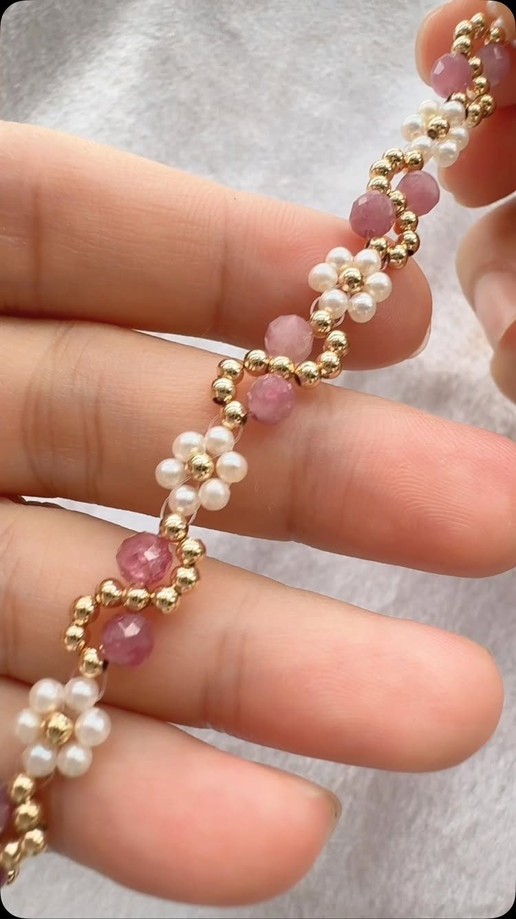 Handmade beaded bracelet with pink gemstones and white pearls held by fingers