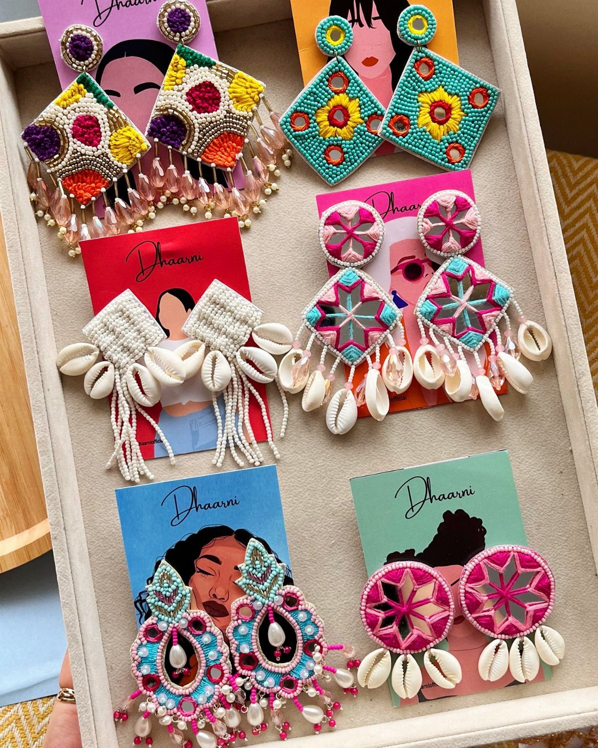 Handmade beaded earrings with shells and tassels displayed on branded gift cards.