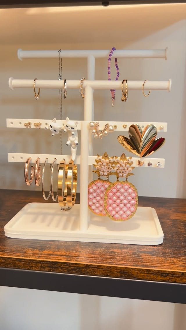 12 Ideas for Organizing Jewelry: Wall, Drawer & Travel Storage 5 White jewelry stand holding gold hoops, rings, and pink earrings on wooden table