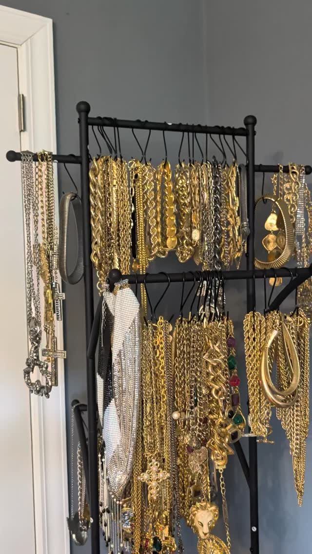 12 Ideas for Organizing Jewelry: Wall, Drawer & Travel Storage 3 Black metal jewelry rack holding many gold and silver necklaces and chains.