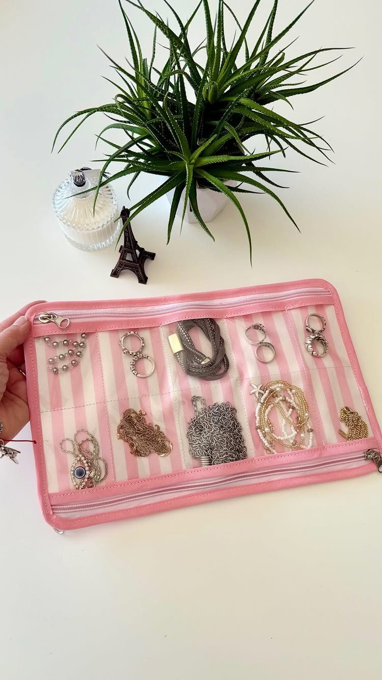 12 Ideas for Organizing Jewelry: Wall, Drawer & Travel Storage 11 Pink striped zippered travel pouch holding various gold and silver jewelry pieces.