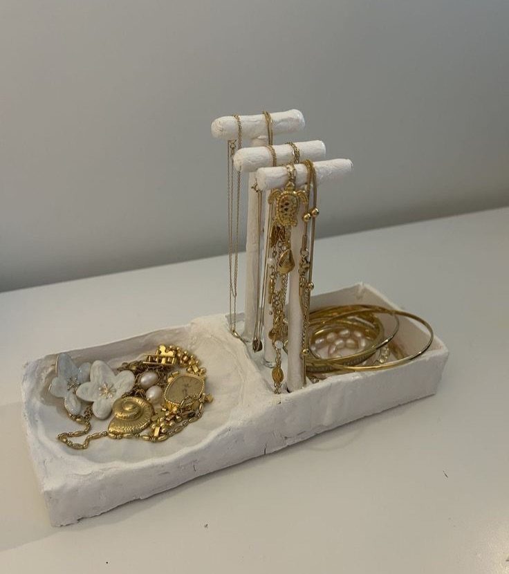 10 Jewellery Holder Ideas for Every Dressing Table 8 White clay jewelry holder with vertical posts and tray holding gold necklaces and bracelets