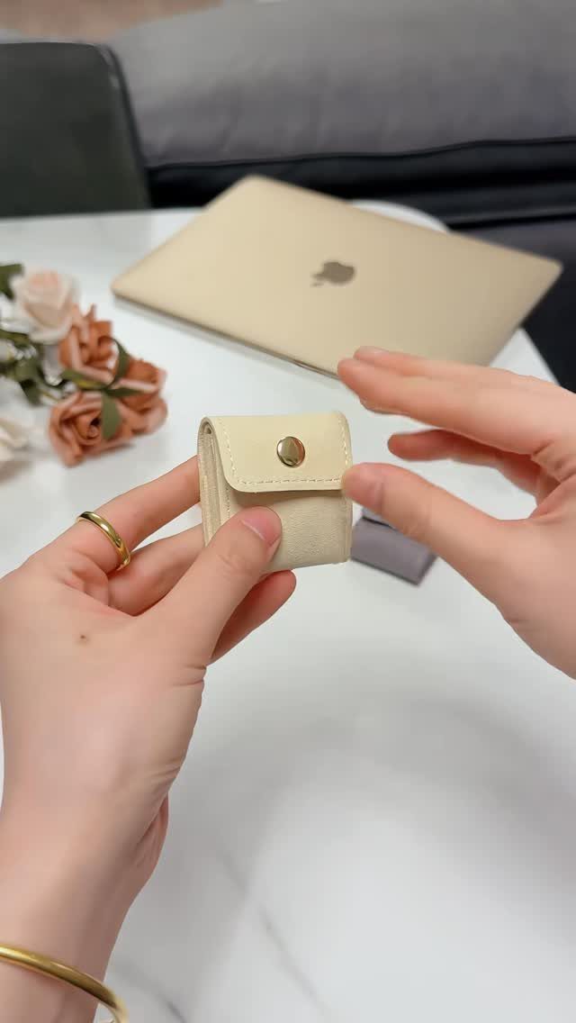 10 Jewellery Holder Ideas for Every Dressing Table 6 Small beige travel jewelry case held by hands on a white table.