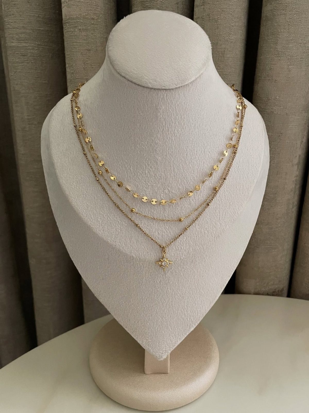 19 Jewelry Aesthetic Gold Ideas for Easy Style 5 Three layered gold necklaces with a star pendant on a white jewelry bust.