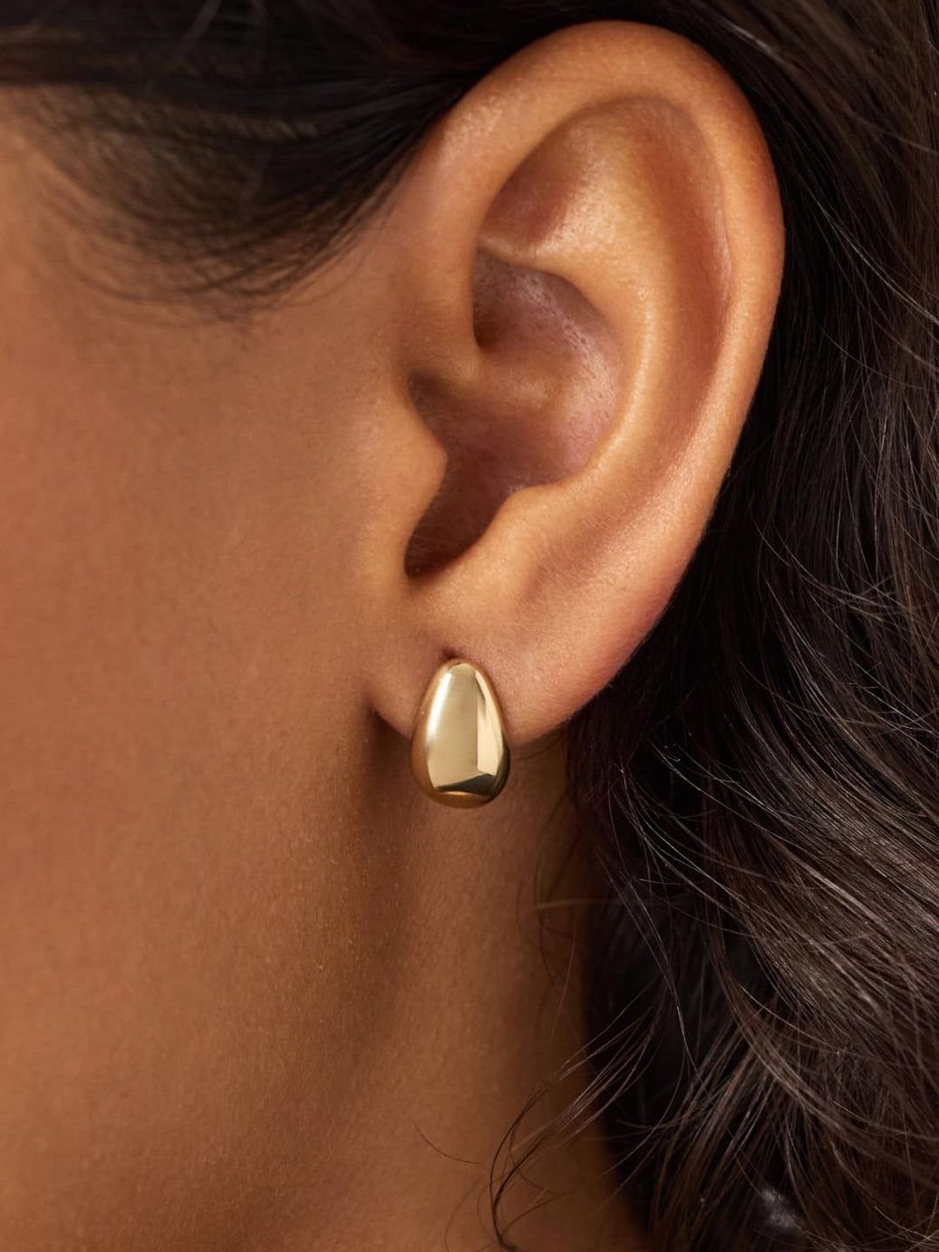 19 Jewelry Aesthetic Gold Ideas for Easy Style 1 Gold stud earring with a smooth organic shape worn on a person's ear