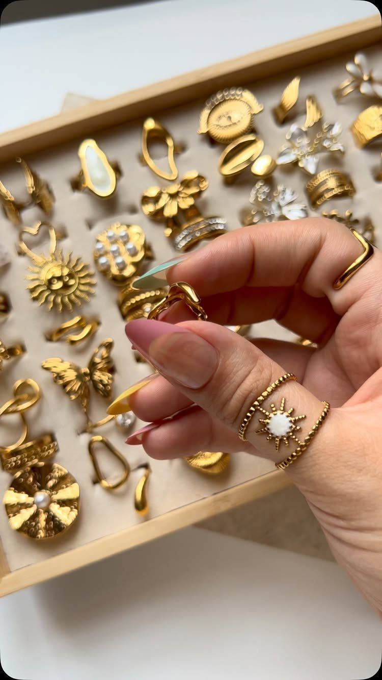 19 Jewelry Aesthetic Gold Ideas for Easy Style 13 Hand selecting from a wooden tray of various bold gold statement rings.