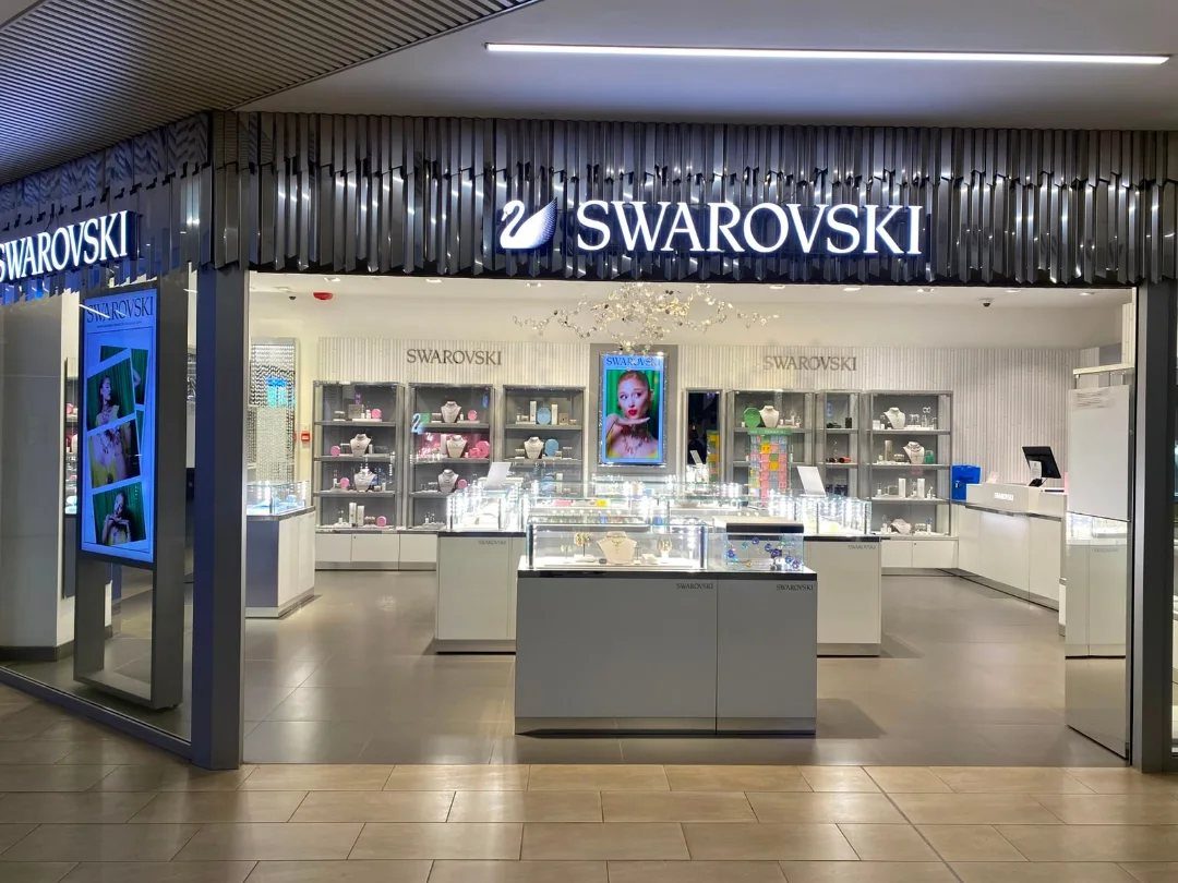 9 Jewelry Brand Logos From Tiffany Blue to Swarovski Swan 3 Swarovski store storefront featuring the glowing white swan logo and brand name.