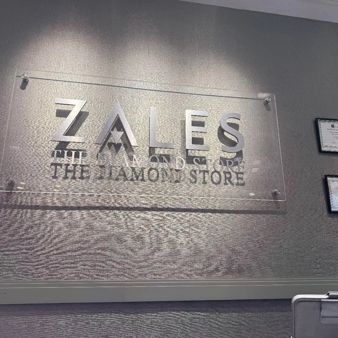 9 Jewelry Brand Logos From Tiffany Blue to Swarovski Swan 5 Zales logo and The Diamond Store text on a clear acrylic wall plaque.