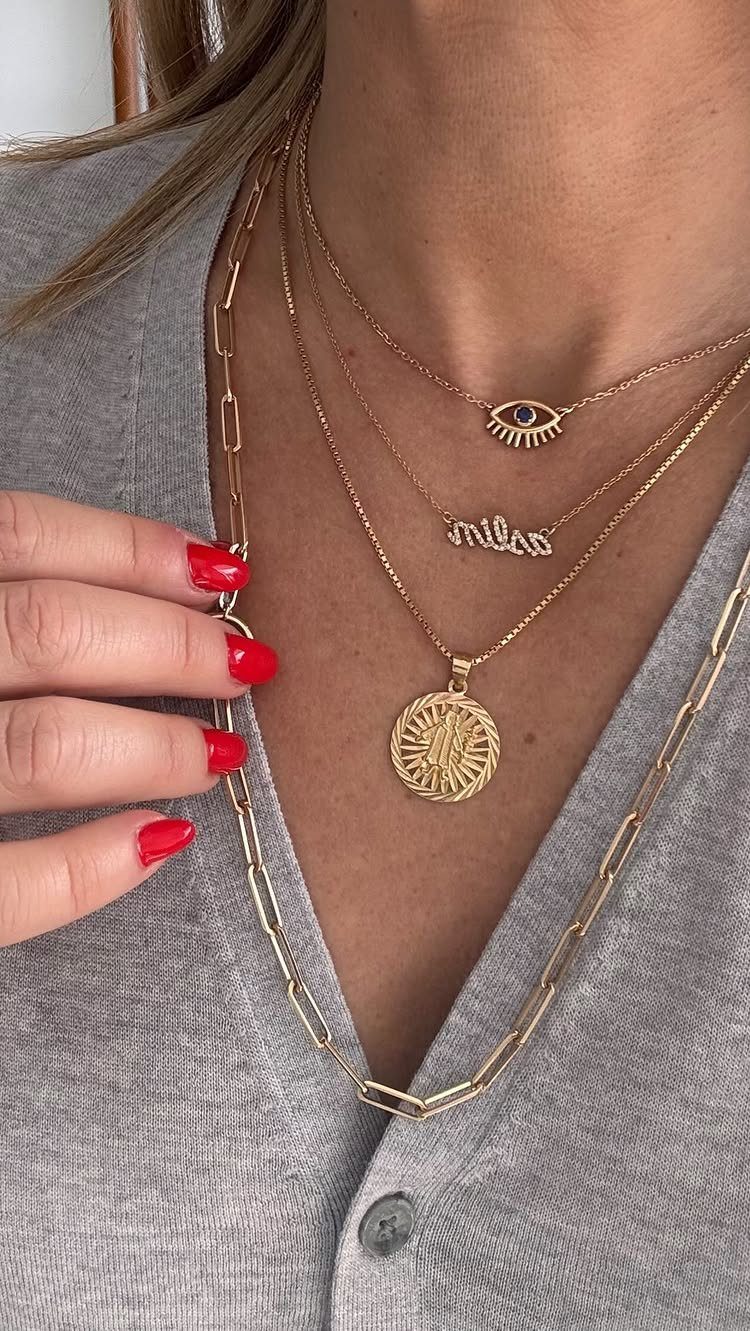 Four layered gold necklaces of different lengths worn on a person's neck.
